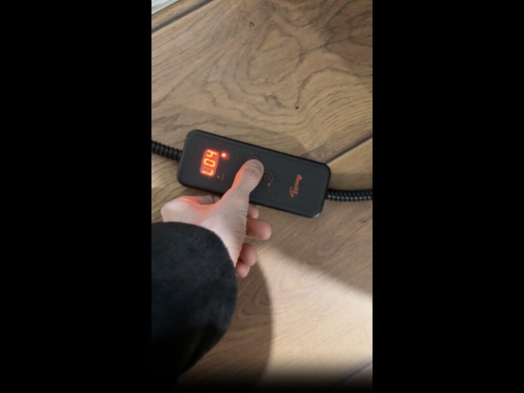 手がリモコンのボタンを押している