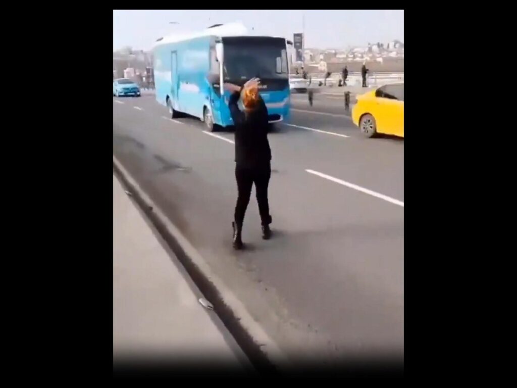 道路でバスの前に立ちはだかる女性