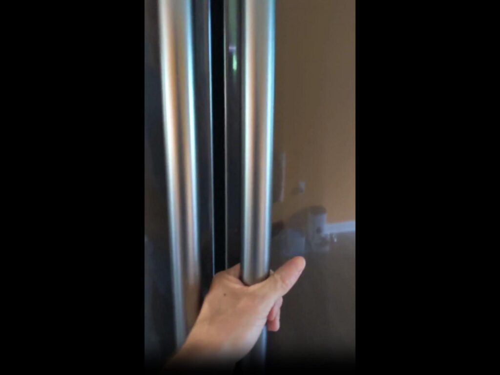 冷蔵庫の取っ手を掴んでいる手