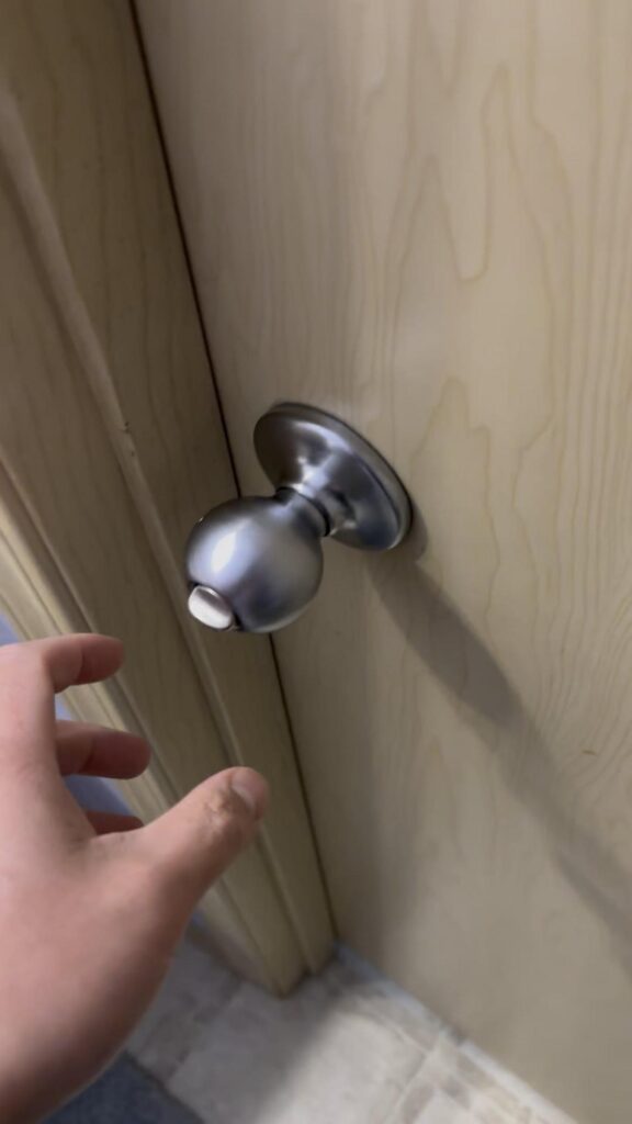 肌色の人間がドアノブに手を伸ばす