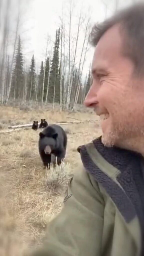 笑顔の男性と歩く黒いクマの親子