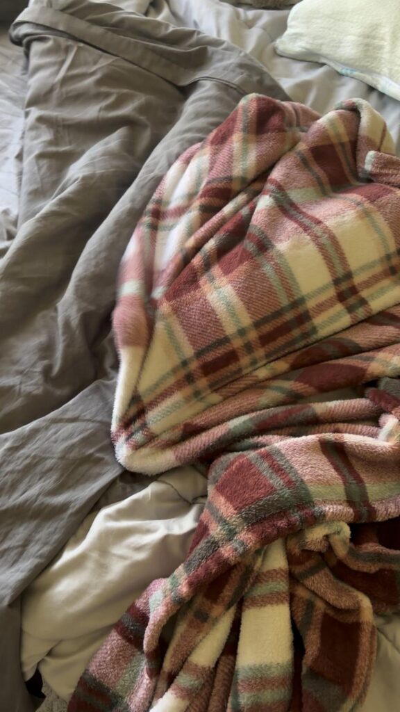 ベッドの上の赤系チェック柄の毛布