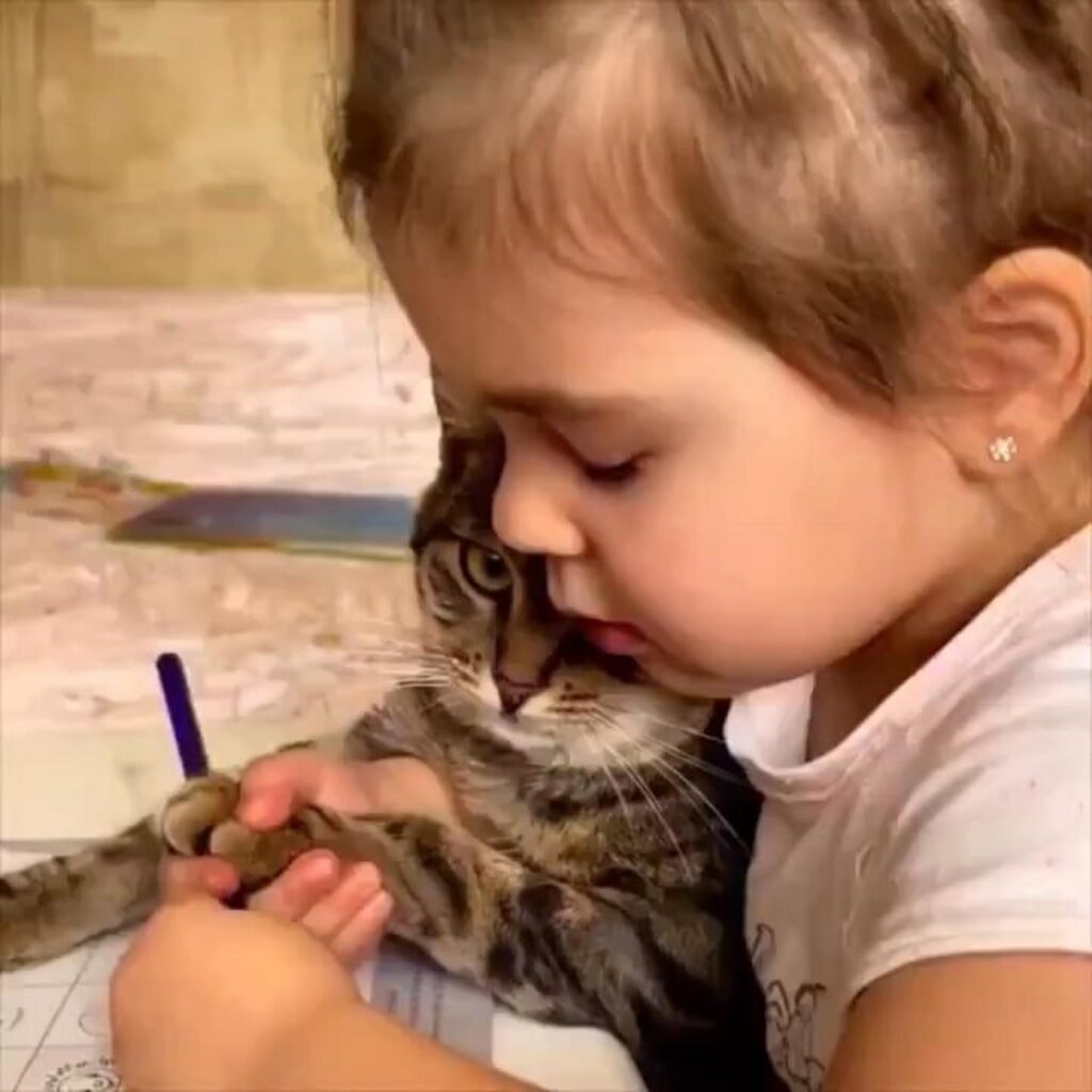 茶色の猫と女の子がお絵描きしている