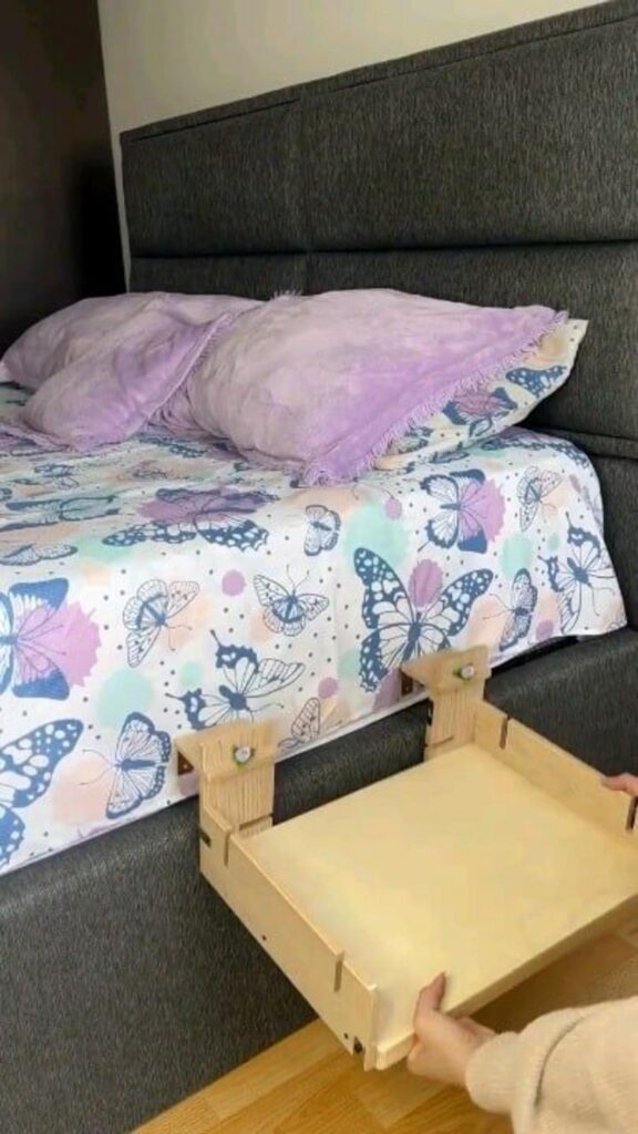 ベッドの横に木製の棚を設置している様子